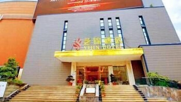 A modern building with a large digital display on the facade, a set of stairs leading to the entrance, and a clear sky in the background. - Chengdu Yijin Hotel (Chengdu)