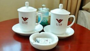 A table with two white teacups and saucers, a teapot, and a small dish with a tea bag. - Lin Yi Hotel (Linyi)