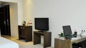 A hotel room with a bed, a TV, a desk with a laptop, a coffee table with cups, and a sofa. - Lin Yi Hotel (Linyi)