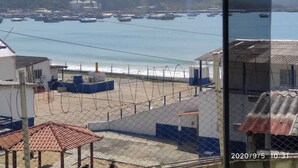 Une vue sur la côte, avec des bateaux, une zone délimitée par une clôture et des bâtiments co couverts de tuiles rouges.