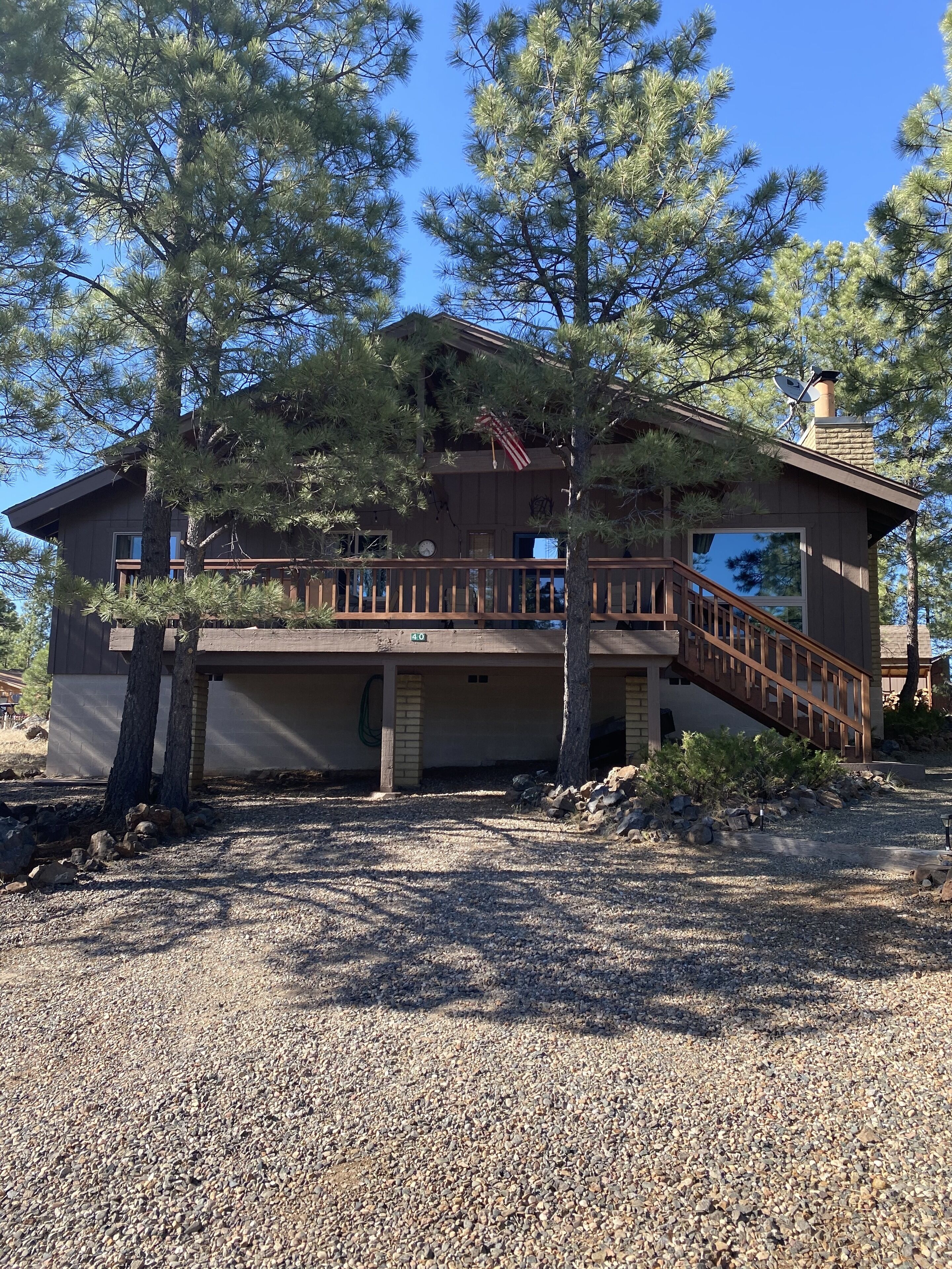 Rustic Cabin with modern amenities, large front deck surrounded by pine trees.