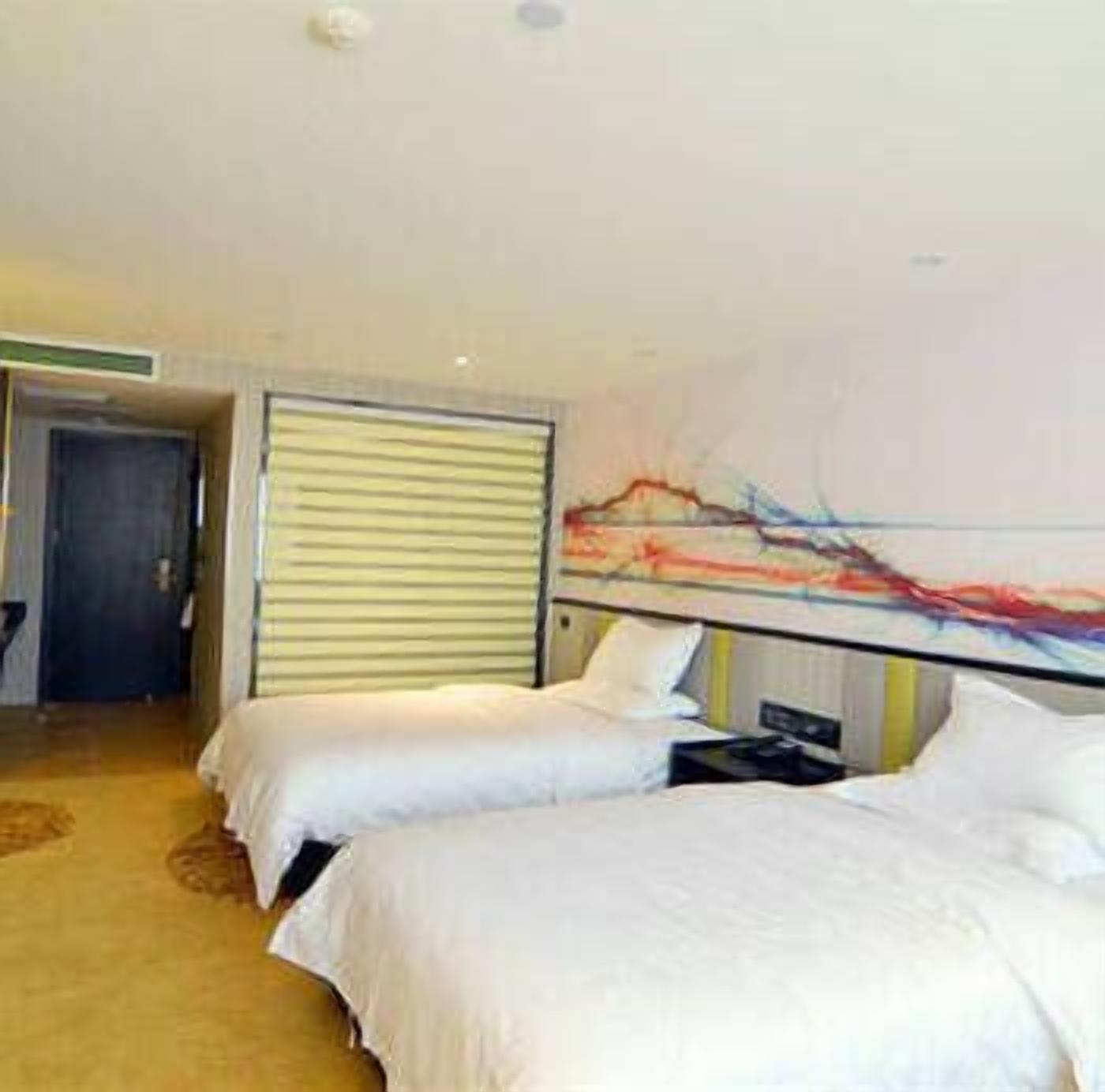 A hotel room with two beds, a large abstract painting on the wall, and a door leading to another room.