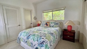 A bedroom with a bed, two bedside tables, a window, and a door.