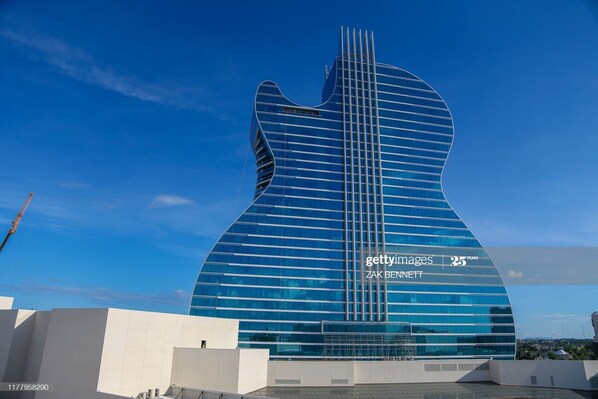 A modern building with a guitar-shaped design, featuring a curved facade and a series of vertical lines.
