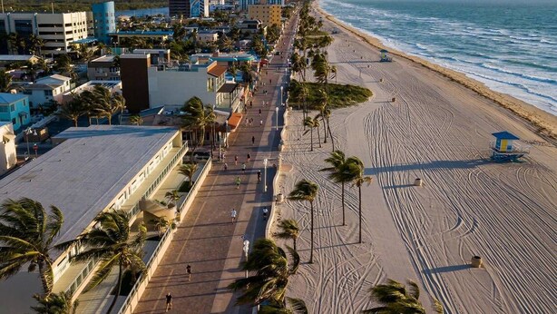 A coastal cityscape with a wide promenade, palm trees, and beachfront properties. - Family Retreat w/ Dual Masters - Screened Pool, Media Game Room & Beach 6 Miles (Hollywood)