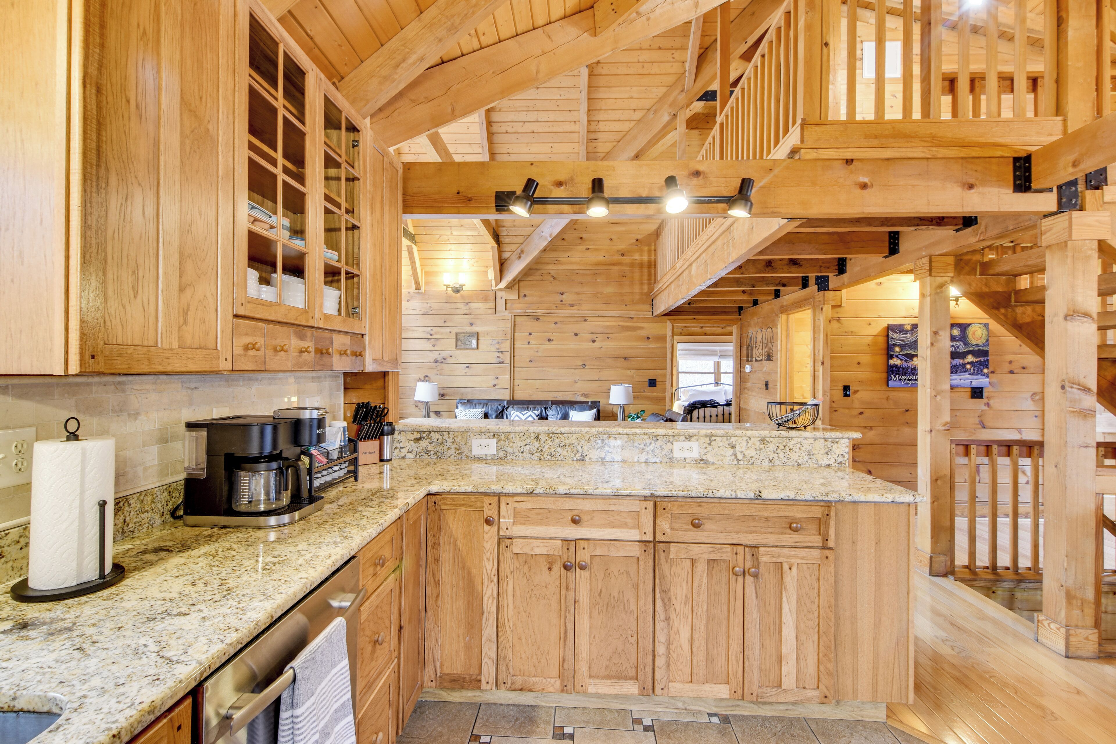 A wooden cabin interior with a kitchen area featuring granite countertops, wooden cabinets, and a built-in stove.