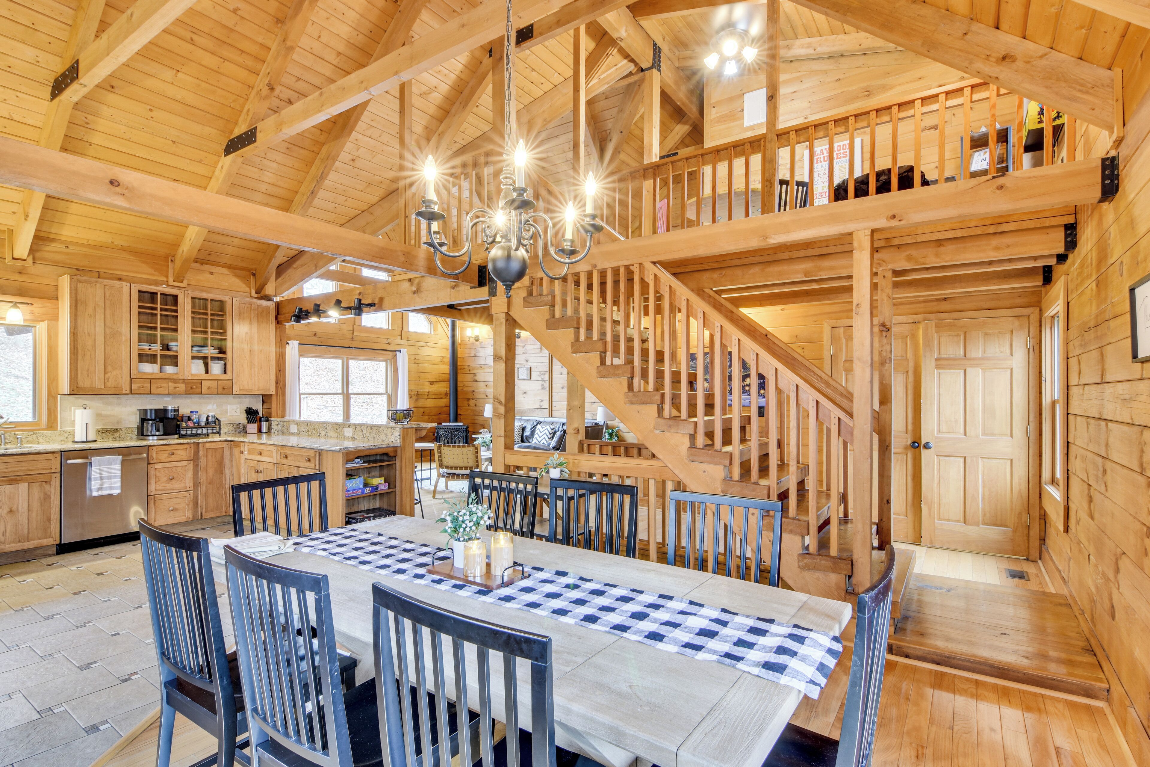 A spacious wooden cabin with a dining area, kitchen, and a staircase leading to an upper level.