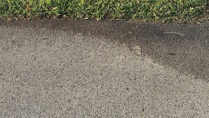 Ein Wohngrundstück mit einer Rasenfläche, einem gelben Feuerhydranten und einem weißen Auto, das auf der Einfahrt geparkt ist.