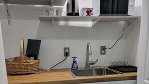 Eine kleine Küche mit Kühlschrank, Mikrowelle, Spüle und einem Hängeschrank.