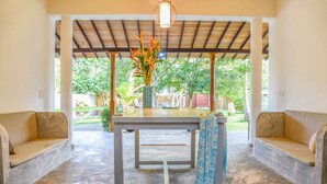 Un espace extérieur abrité, aménagé avec une table et un vase de fleurs.