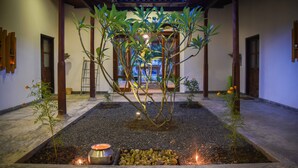 Un jardin japonais traditionnel avec un arbre central, des lanternes en pierre et une structure en bois.