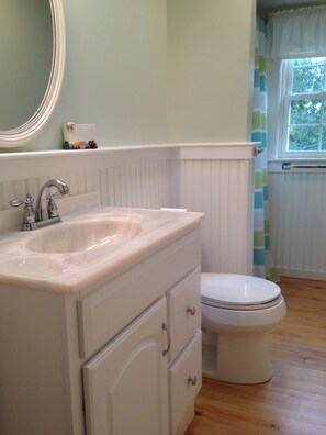Une salle de bain avec un lavabo blanc, un miroir et des toilettes.