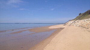 A beach with a rocky embankment and a staircase leading down to the water. - Steps To Bay at Campground Beach, A/C, Heat,Wifi, Outdoor Shower, Gas Grill (Eastham)