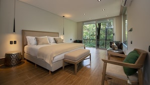 Un dormitorio moderno con una cama grande, un banco de madera y un área de descanso con vistas al exterior.