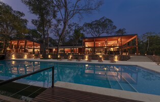 Un moderno resort con piscina, terraza de madera y zona de descanso.
