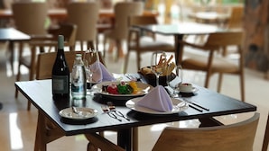 Una mesa de comedor dispuesta con platos, cubiertos, una botella de agua, una botella de vino y una copa.