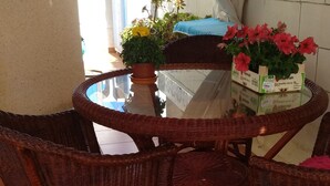 A wicker table with chairs, a potted plant, and a crate of red flowers. - CASA CALA IGORA SPAIN (Torrevieja)