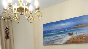 A living room with a sofa, a television, a fireplace, and a painting of a beach scene. - CASA CALA IGORA SPAIN (Torrevieja)