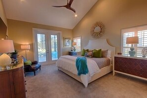 Relax in this serene bedroom with a large bed, dresser, and ceiling fan. Enjoy the view from the large window and access to an outdoor area.