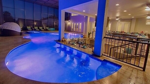 Ein Pool mit geschwungenem Design, umgeben von Liegestühlen und einer überdachten Sitzgruppe.