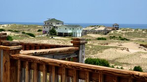 Ein Anwesen direkt am Strand mit Holzterrasse, einem großen Haus und einem Geländewagen.