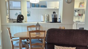 A cozy living room with a brown armchair, a wooden dining table with chairs, and a kitchen area in the background. - I'm the ONE! The CONCH Walk to Beach and Times Square (FMB)