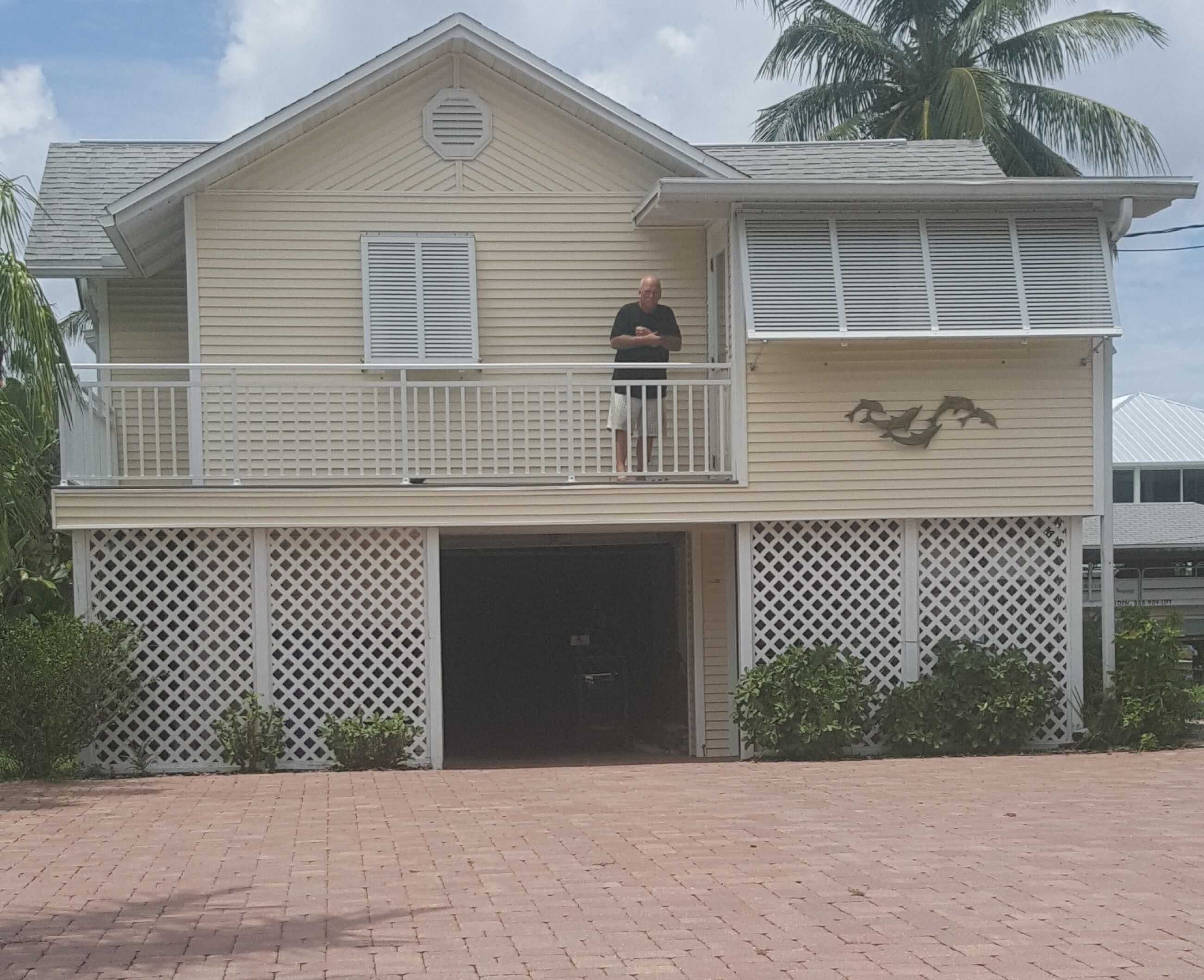 Une maison à deux étages avec un balcon, un garage et un mur décoratif.