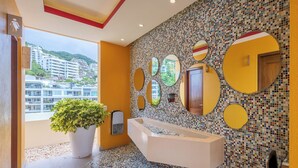 Ein modernes Badezimmer mit einer großen Badewanne, mehreren Spiegeln und einer Wand mit Mosaikfliesen.