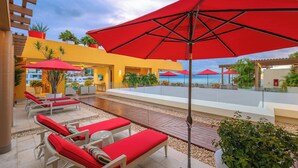 Eine Dachterrasse mit roten Sonnenschirmen, Liegestühlen und Topfpflanzen.
