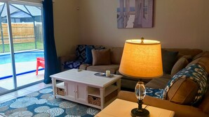 Un salon avec une table basse blanche, une lampe, un canapé et un tableau accroché au mur.