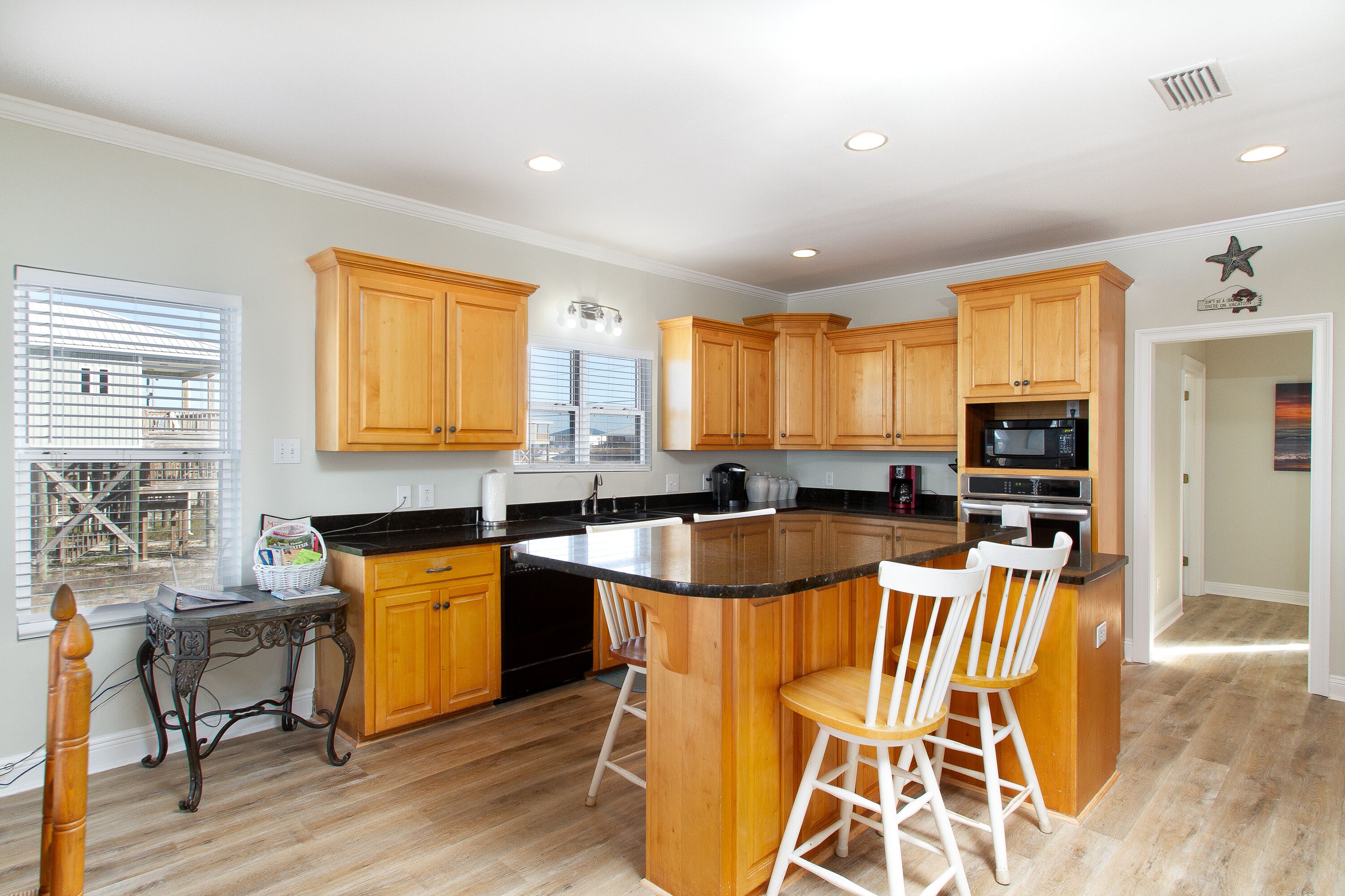A modern kitchen with wooden cabinets, a large island with bar stools, and a built-in microwave.