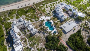 Une vue aérienne d’un complexe hôtelier comprenant plusieurs bâtiments, une grande piscine et une plage.
