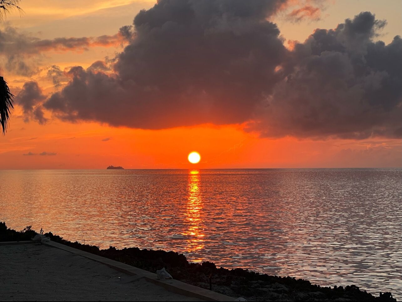 A sunset over a calm sea with a distant island.