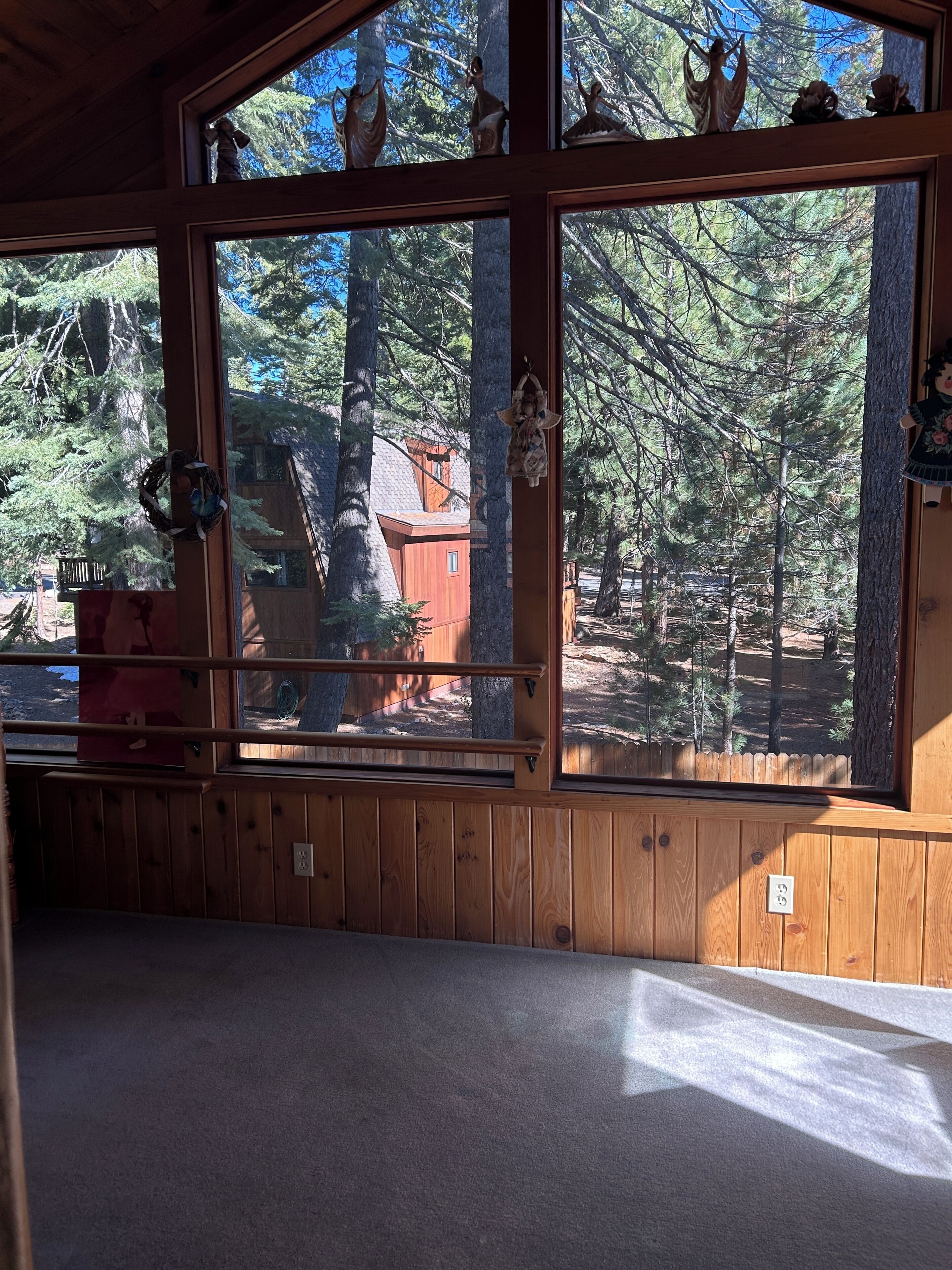 A cabin with large windows, wooden walls, and a view of a forest.