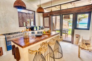 Una cocina con encimera de madera, estufa y ventana grande con vista a la playa.