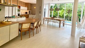 A modern kitchen with a wooden island, white cabinets, and a large window overlooking a lush garden.