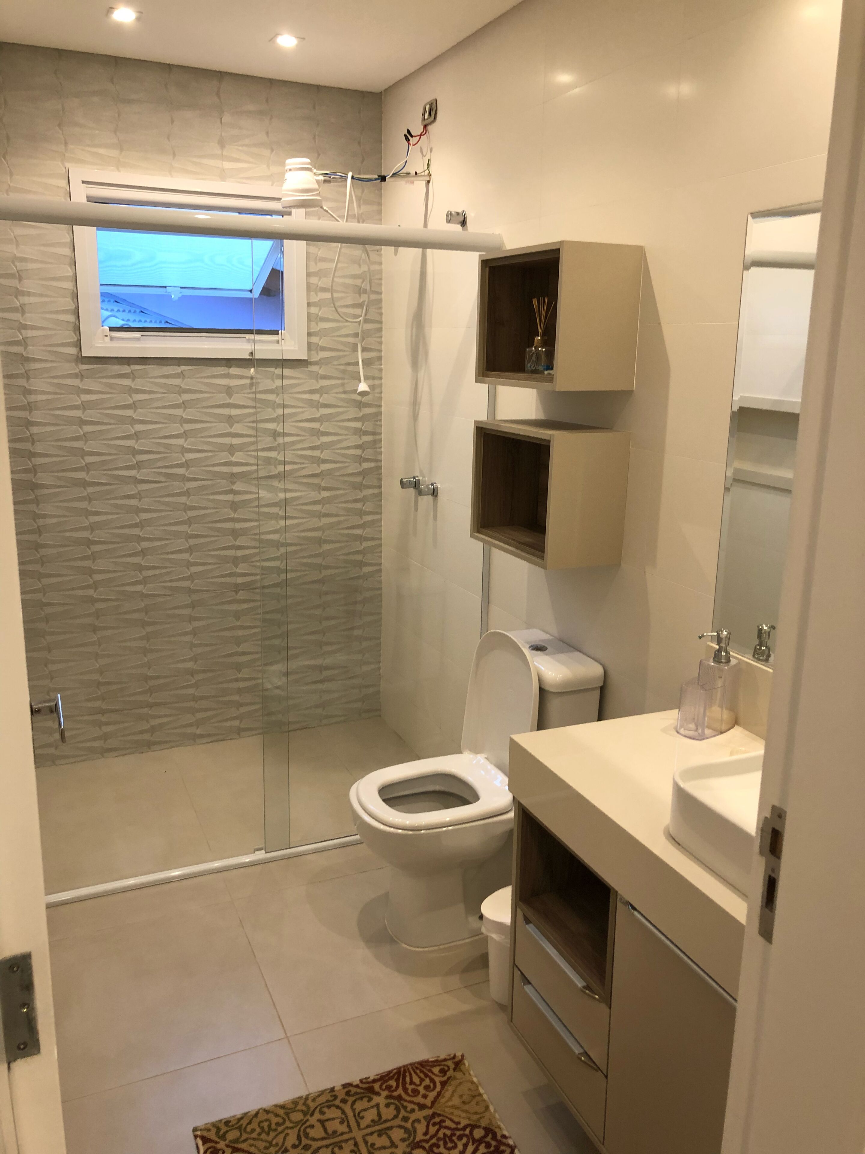 Une salle de bain moderne dotée d’une douche à parois de verre, de toilettes et d’un meuble-lavabo avec un miroir.