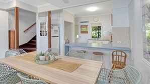 Una cocina moderna con un cartel de 'VACANCY', un comedor con una mesa y sillas de madera, y una escalera que lleva a otro nivel.