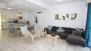 Una sala moderna con un sofá, sillas, una mesa de centro y un comedor con una mesa y sillas.