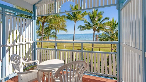 Un espacio al aire libre techado con vista a la playa, con una mesa y sillas.