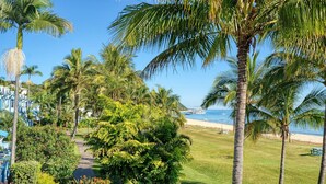 Un resort tropical con palmeras, una playa y un cielo azul despejado.
