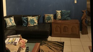 Un saló amb un mural gran de peixos a la paret, un sofà de cuir negre i un moble de fusta.