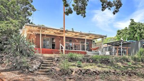 Una casa rústica amb un porxo cobert, una petita zona d'estar a l'exterior i una escala que condueix a l'entrada.