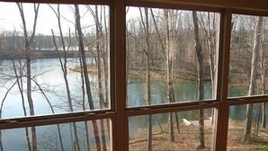 Une pièce dotée d’une grande fenêtre donnant sur un lac entouré d’arbres.