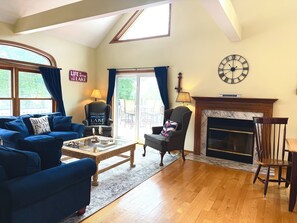A living room with a fireplace, a clock, and a view of the outdoors. - Fantastic Vacation Rental in Lake Como, Sleeps 8-12 (Lake Geneva)
