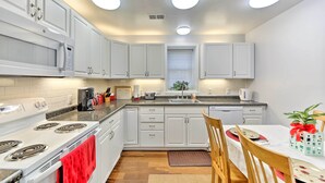 Une cuisine moderne avec des meubles blancs, un four à micro-ondes encastré et un coin repas comprenant une table et des chaises.
