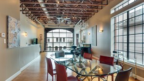A modern dining area with a glass table, red chairs, and a high ceiling with exposed beams. - Montrose NY Style Brick Home with a chef kitchen! (Houston)