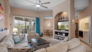 A living room with a sofa, coffee table, and TV. There is a dining area with a table and chairs. - Endless Summer Villa, Spacious 4 bedroom pool home w/spa and tropical garden and themed kids rooms (Polk County)