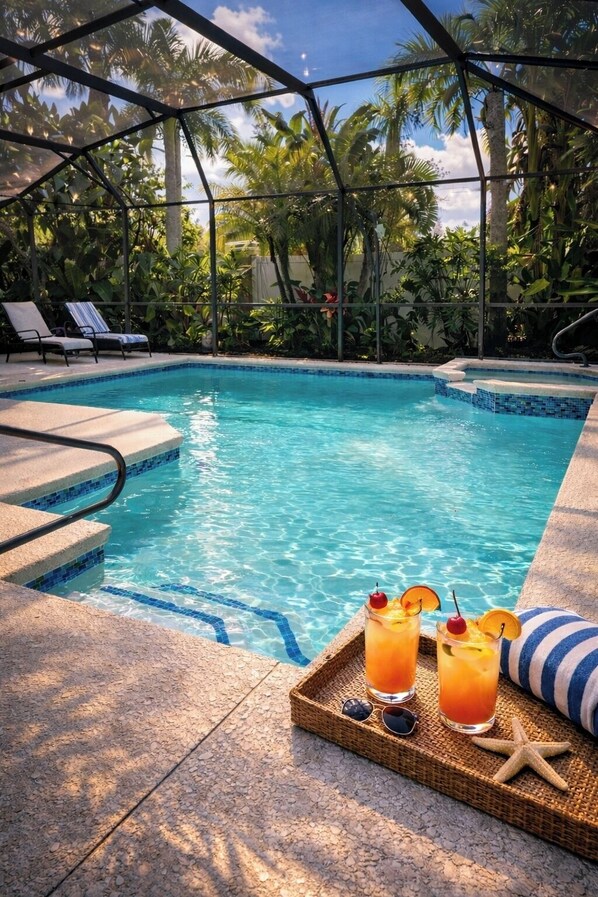 Une piscine à l’eau d’un bleu cristallin, entourée de chaises longues et de plantes tropicales.
