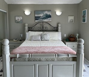 A neatly made bed with a patterned bedspread, a headboard with decorative finials, and wall-mounted light fixtures.
